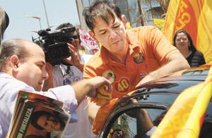 Roberto Cláudio e o governador Cid Gomes pregando adesivos em veículos de fortalezenses na Praia do Futuro, fim da manhã de ontem 