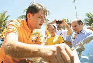 Cid Gomes ao lado de Roberto Cláudio, na Praia do Futuro, fim da manhã de ontem, prega adesivo em veículos de simpatizantes do candidato